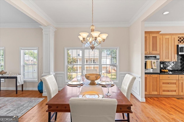 dining area with crown molding, an inviting chandelier, decorative columns, and light wood-type flooring