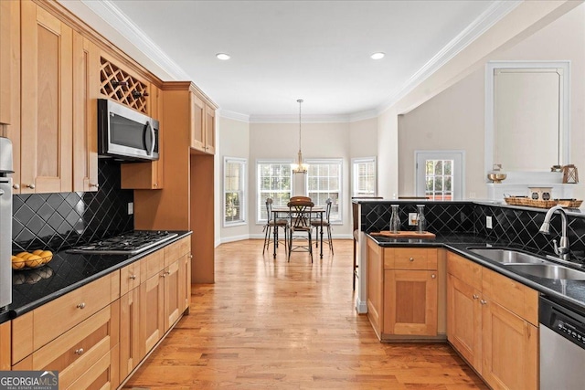 kitchen with sink, appliances with stainless steel finishes, hanging light fixtures, ornamental molding, and decorative backsplash