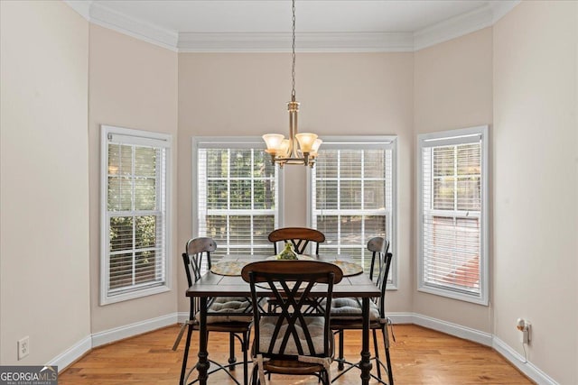 dining room featuring ornamental molding, a chandelier, light wood-type flooring, and a wealth of natural light