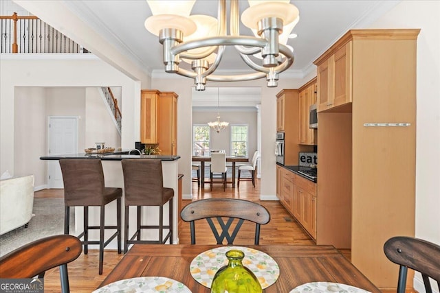 kitchen featuring decorative light fixtures, ornamental molding, kitchen peninsula, a notable chandelier, and hardwood / wood-style flooring