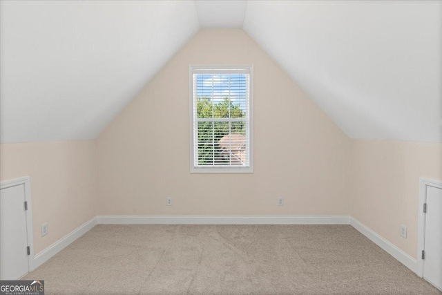 additional living space featuring lofted ceiling and light colored carpet