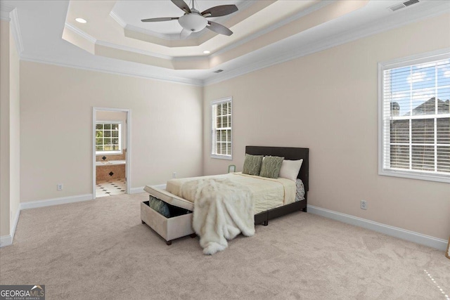 carpeted bedroom with a raised ceiling, ceiling fan, crown molding, and ensuite bath