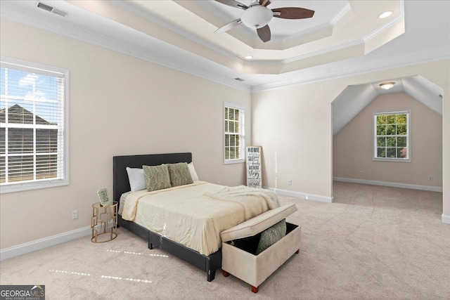 bedroom featuring multiple windows, a raised ceiling, and ceiling fan