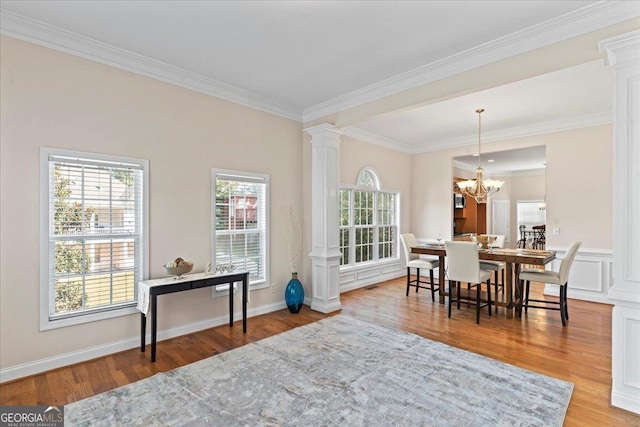 dining area with decorative columns, ornamental molding, hardwood / wood-style flooring, and a notable chandelier