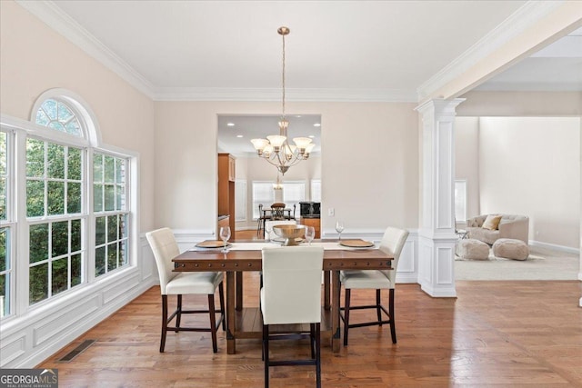 dining room featuring ornamental molding, a chandelier, decorative columns, and light wood-type flooring