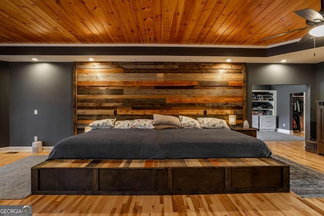 bedroom with a spacious closet, wood-type flooring, wooden ceiling, and ceiling fan