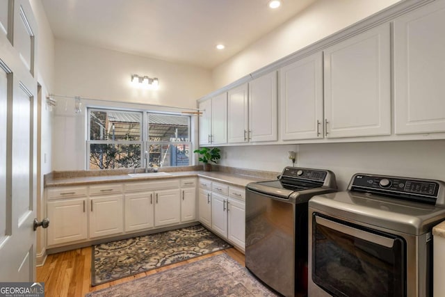 washroom with cabinets, washer and clothes dryer, sink, and light wood-type flooring