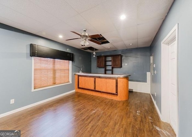 kitchen featuring a drop ceiling, dark wood-type flooring, kitchen peninsula, and ceiling fan