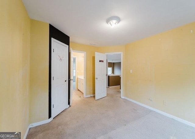 unfurnished bedroom featuring connected bathroom and light colored carpet