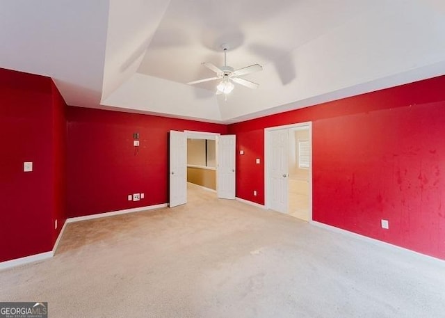 unfurnished bedroom featuring a tray ceiling, ceiling fan, and carpet