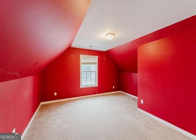 additional living space with vaulted ceiling and carpet flooring