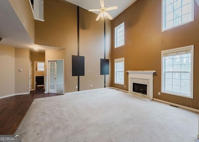 unfurnished living room with a towering ceiling, a healthy amount of sunlight, and a fireplace