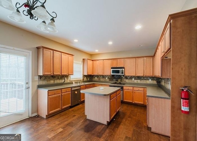 kitchen featuring pendant lighting, sink, appliances with stainless steel finishes, dark hardwood / wood-style floors, and a center island