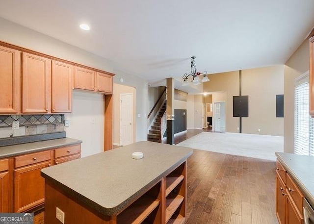 kitchen featuring tasteful backsplash, hanging light fixtures, a kitchen island, and hardwood / wood-style flooring