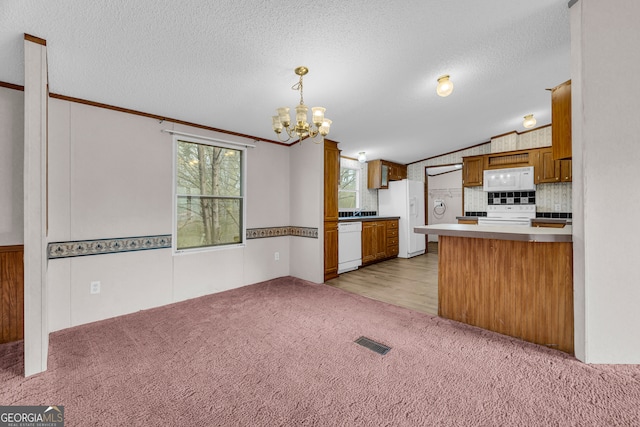 kitchen featuring decorative light fixtures, a textured ceiling, kitchen peninsula, a notable chandelier, and white appliances