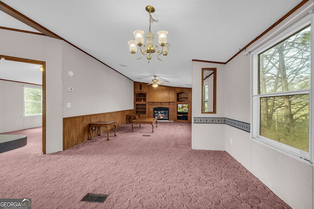 interior space with lofted ceiling, ceiling fan with notable chandelier, a textured ceiling, and carpet flooring