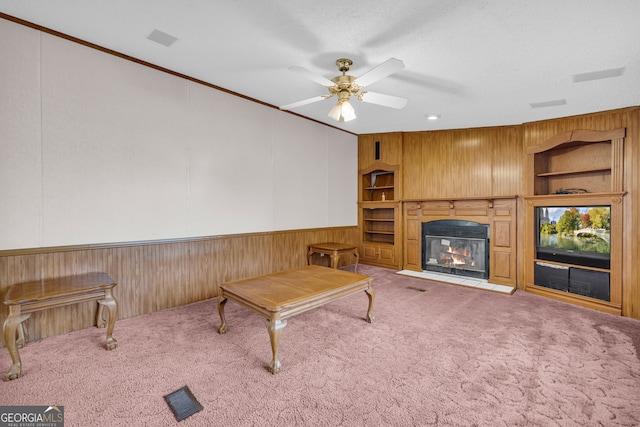 living room featuring ornamental molding, carpet flooring, built in features, and a textured ceiling