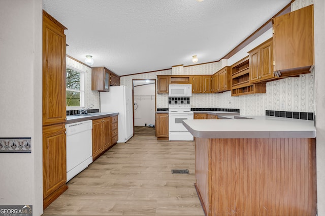 kitchen featuring sink, ornamental molding, white appliances, kitchen peninsula, and a textured ceiling