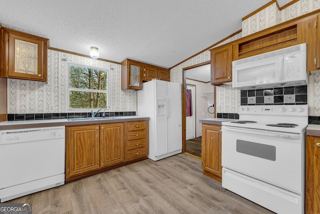 kitchen with lofted ceiling, sink, light wood-type flooring, crown molding, and white appliances