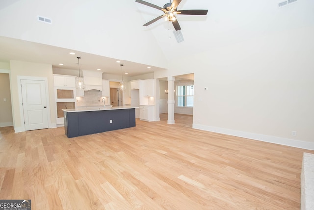 unfurnished living room featuring sink, light hardwood / wood-style flooring, high vaulted ceiling, and ceiling fan