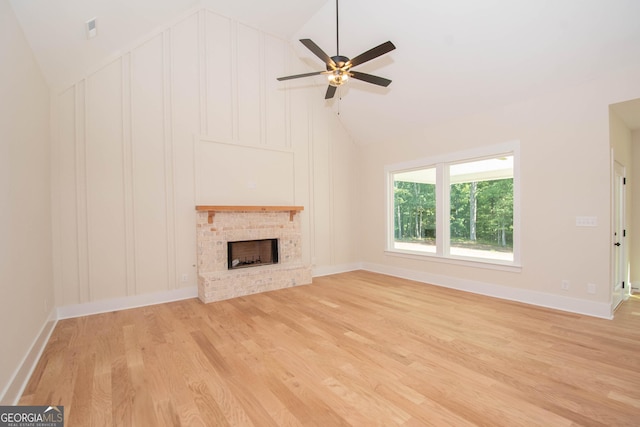 unfurnished living room featuring a brick fireplace, vaulted ceiling, light hardwood / wood-style floors, and ceiling fan