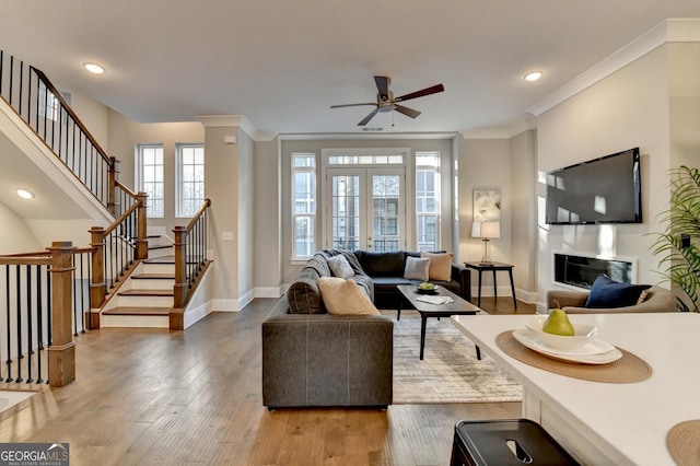 living room featuring wood-type flooring, ornamental molding, french doors, and ceiling fan