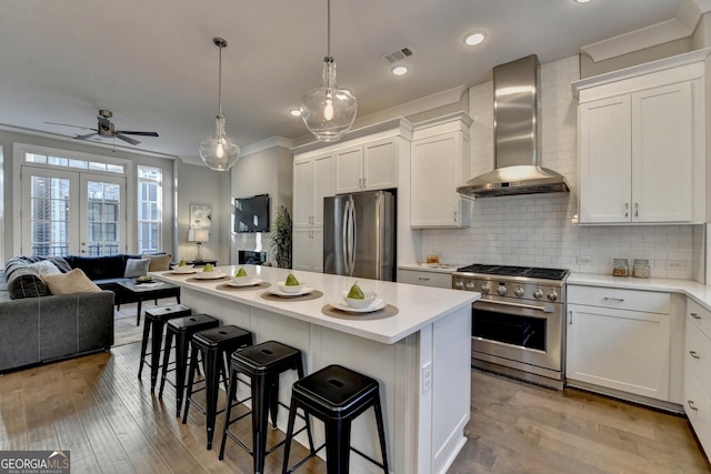 kitchen with wall chimney range hood, a center island, white cabinets, and appliances with stainless steel finishes