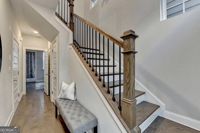 staircase with hardwood / wood-style floors and a high ceiling