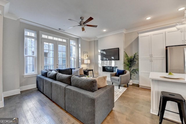 living room featuring crown molding, ceiling fan, light hardwood / wood-style flooring, and french doors