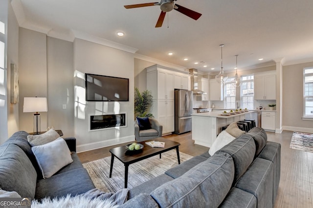 living room with crown molding, ceiling fan, and light hardwood / wood-style flooring