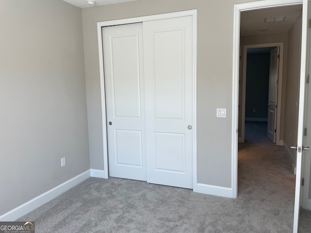 unfurnished bedroom featuring light colored carpet and a closet