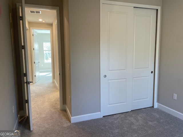 unfurnished bedroom with dark colored carpet and a closet