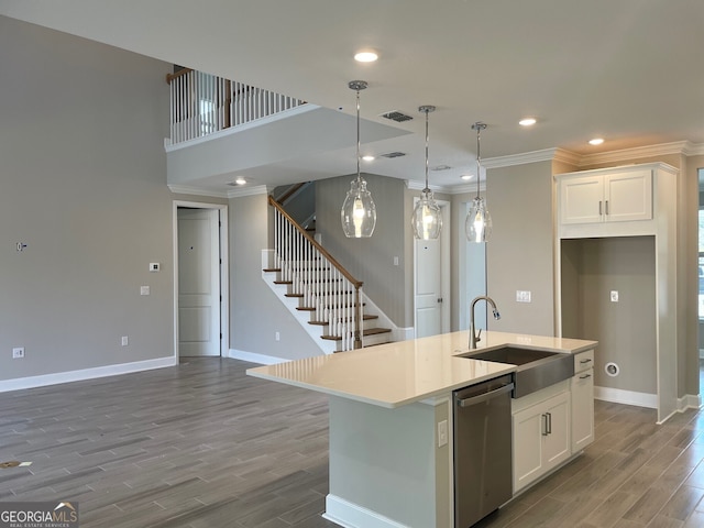 kitchen featuring sink, dishwasher, hanging light fixtures, white cabinets, and a center island with sink