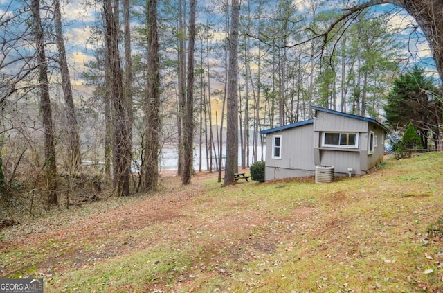 view of home's exterior with a water view, a lawn, and central air condition unit