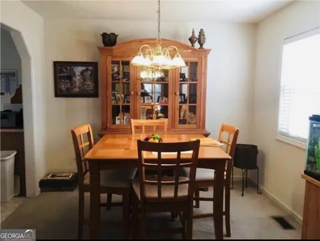 carpeted dining room with a notable chandelier