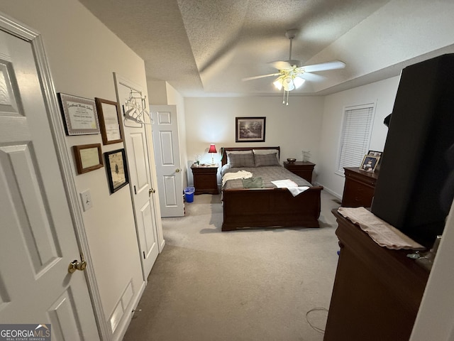 carpeted bedroom featuring ceiling fan, a raised ceiling, and a textured ceiling