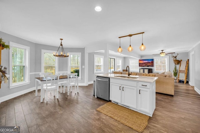 kitchen with pendant lighting, dishwasher, an island with sink, sink, and white cabinets