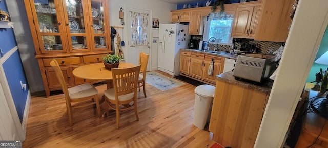 kitchen featuring sink, white appliances, backsplash, light brown cabinets, and light wood-type flooring