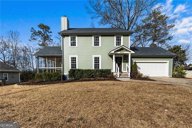 colonial home featuring a garage and a front lawn