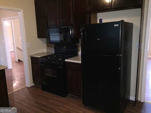 kitchen with dark wood-type flooring, dark brown cabinets, and black appliances