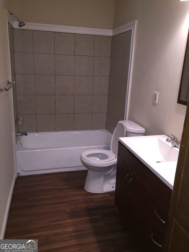 full bathroom with tiled shower / bath combo, vanity, hardwood / wood-style floors, and toilet