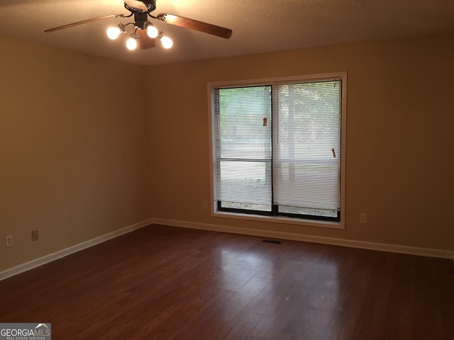 unfurnished room featuring dark wood-type flooring, ceiling fan, and a textured ceiling