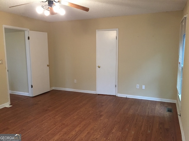 unfurnished room featuring dark wood-type flooring, a textured ceiling, and ceiling fan