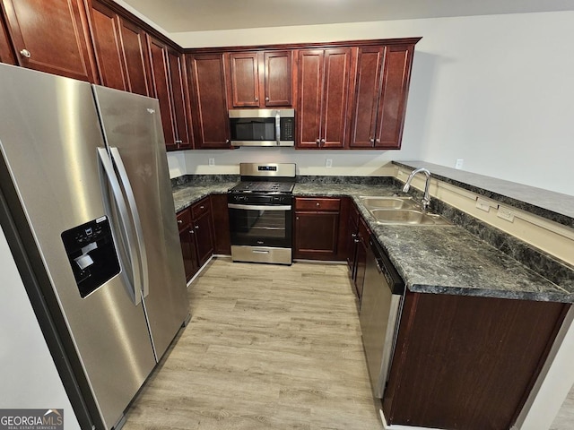 kitchen featuring appliances with stainless steel finishes, kitchen peninsula, sink, and light hardwood / wood-style flooring