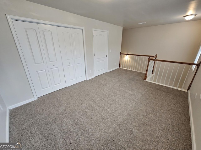 unfurnished bedroom featuring dark carpet and a closet