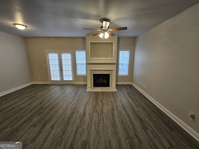 unfurnished living room featuring a high end fireplace, dark hardwood / wood-style floors, and ceiling fan