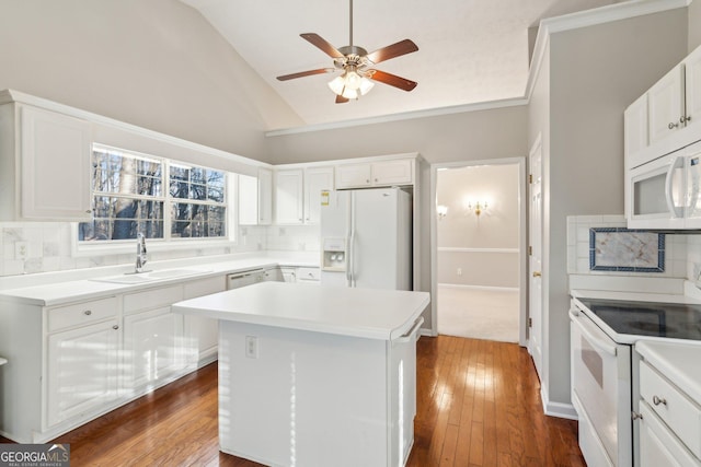 kitchen featuring a center island, white appliances, light countertops, and a sink