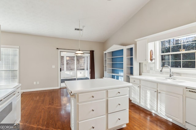 kitchen featuring light countertops, white cabinets, a kitchen island, a sink, and dishwasher