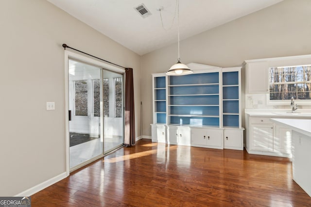 unfurnished dining area featuring dark wood-style floors, vaulted ceiling, visible vents, and a sink