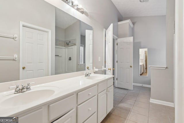 bathroom featuring tile patterned flooring, double vanity, a sink, and walk in shower